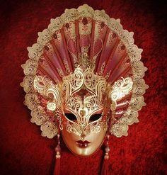 Crafted in sultry red and gold, this decadent mask's most alluring feature is its extended fan-shaped headpiece. Composed of applique, hand-bent metal, and crystals, this mask will lend its wearer an air of regal seductiveness that won't be easily forgotten by those who behold it. Handmade in Italy and is accompanied b Luxury Artistic Masks For Carnival, Luxury Artistic Red Masks And Prosthetics, Traditional Red Masks And Prosthetics For Costume Party, Fantasy Style Red Carnival Masks, Red Masquerade Mask For Carnival Festivals, Red Carnaval Festival Masquerade Mask, Red Full Face Carnival Mask, Full Face Red Mask For Masquerade, Red Full Face Mask For Masquerade