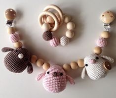 three crocheted animals and two wooden beads on a white surface with one bead in the shape of an animal