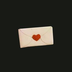 a white envelope with a red heart on the front and back flap, against a black background