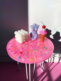 there is a pink table with two small bears on it and an ice cream cone