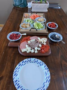 a wooden table topped with plates and bowls filled with food next to a cutting board