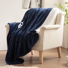 a white chair with a blue blanket on it and a remote control in the back