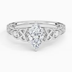 a white gold engagement ring with a pear shaped diamond in the center and an intricate band around it