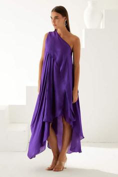 Violet one shoulder high-low dress in a pleated draped solid base. - Aza Fashions Pre-draped Sleeveless Summer Dress, Spring Pre-draped Asymmetrical Dress, Summer Cocktail One Shoulder Pre-draped Dress, Silk Midi Dress With Folds For Summer, Pre-draped One Shoulder Summer Dress, One Shoulder Pre-draped Maxi Dress, Chic Dresses With Asymmetrical Hem And Folds, Pre-draped Asymmetrical Summer Cocktail Dress, Pre-draped Asymmetrical Summer Dress