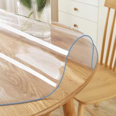 a wooden table with a clear plastic covering on it and a vase filled with flowers