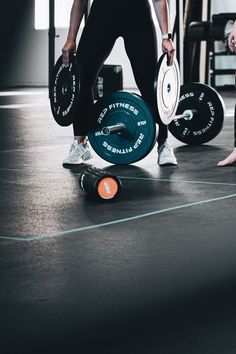 a man holding two weight plates on top of a skateboard