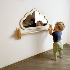 a little boy standing in front of a mirror with a wooden frame on the wall