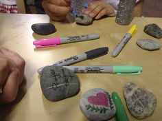 several rocks with writing on them are sitting on a table next to markers and pens