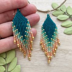 a pair of blue and gold beaded earrings sitting on top of a wooden table