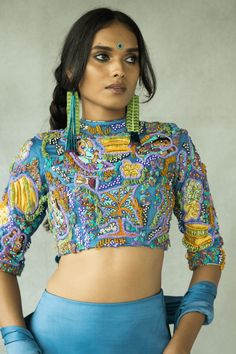 High neck hand embroidered blouse with key hole at the back. CLOSURE AND DETAILS: Side closure with a concealed zip, High neck fully embroidered blouse with key hole detail at the back, Fabric patchwork embroidery with a mix of quirky fun beads FABRICS: Cupro Satin COLOR: Denim blue base with hints of lemon yellow and chili green COMPONENTS: 1 WASH CARE: DRY CLEAN ONLY Bohemian Tops With Multicolor Embroidery And Unstitched Blouse, Fitted Party Blouse With Multicolor Embroidery, Fitted Multicolor Embroidery Blouse For Party, Embellished Multicolor Blouse For Festivals, Traditional Multicolor Embroidery Tops For Party, Fitted Multicolor Blouse With Geometric Embroidery, Fitted Multicolor Top With Geometric Embroidery, Multicolor Embroidered Blouse For Party Festivals, Party Blouse With Multicolor Embroidery For Festivals