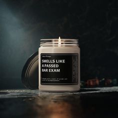 a candle that says smells like a passed bar exam sits on a table in front of a dark background