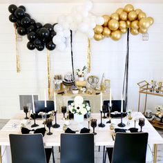 a table with black chairs and gold balloons