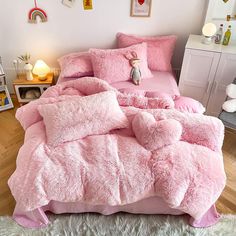 a bed with pink comforters and pillows in a room next to a teddy bear