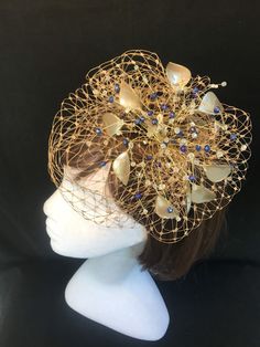 Delicate gold fascinator with scatter of blue crystals, This design can also be made without the blue crystals and be replaced with clear ab crystals ( please note this on your order notes) This design is a beautiful selection of glass effect leaves and wire crystal stems clustered together amongst a fine layer of veiling and set onto a fine comfort base tiara band. As with all our designs, this piece can be made exact to the image or in any colour combination to match in with your outfit. If a Gold Crown Costume Headpiece For Weddings, Gold Evening Fascinator With Pinched Crown, Elegant Gold Headpieces As Gift, Elegant Gold Headpieces For Gift, Gold Hair Accessories For Wedding, Gold Headband Fascinator For Evening, Elegant Gold Fascinator As Gift, Gold Crown Headpiece For Evening, Elegant Gold Headpiece With Pinched Crown