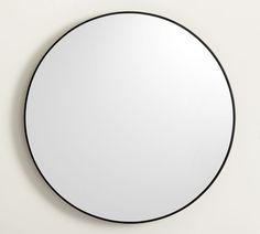 a round mirror mounted on the wall with black trim around it's edges and bottom edge