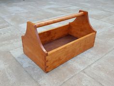 an empty wooden box sitting on the ground in front of a brick flooring area