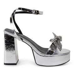 Step into the spotlight with Isabella, the silver platform sandal that will elevate any outfit! Featuring a removable crystal bow, you can play up the glamour or keep it simple. Heel Height 5" Platform height 1.5" Material Vegan Leather Glamorous Bow Sandals For Night Out, Glamorous Silver Heels With Bow, Glamorous Evening Platform Sandals, Silver Platform Heels For Prom, Luxury Silver Heels For Prom, Spring Silver Heels With Bow, Glamorous Platform Sandals For Gala, Chic Silver Sandals For Prom, Silver Platform Sandals For Wedding