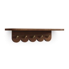 a wooden shelf with four brass hooks on the top and one is hanging from it's side