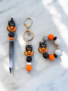 three halloween themed items on a marble surface with a pen and keychain in the foreground