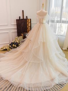 a wedding dress is displayed on a mannequin in front of a large window