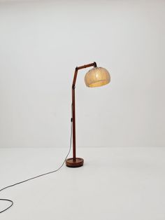 a lamp with a wooden base and a white shade on the light bulb is plugged in