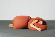 a woman wrapped in a blanket is laying on the floor with her eyes closed and hands behind her head