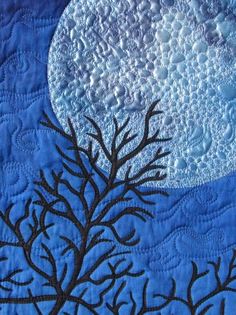 a blue quilt with a tree and moon in the background