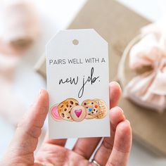 a person holding up a small gift tag with two cookies on it that says paris well with a new job