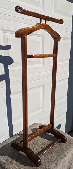 a wooden coat rack in front of a garage door with a shadow on the ground