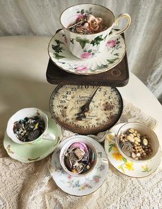 there are three teacups on the table and one has a clock in it