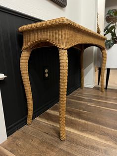 a wicker table sitting on top of a hard wood floor next to a wall