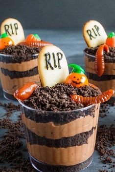 three halloween desserts in plastic cups with dirt on the ground