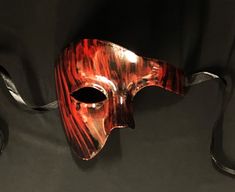 This Phantom mask is hand painted in a sold black then brushed red to give an abstract look. Mask is fully sealed and has a nice gloss look, Great for any Masquerade event or mask costume party! Size 6.5"W x 5.5"H. Color red and black. Red Masquerade Mask Men, Red Mask Aesthetic, Artistic Red Masks And Prosthetics For Costume Party, Black Masks For Halloween Gift, Black Halloween Masks As Gifts, Artistic Red Mask For Costume Party, Artistic Red Masks For Costume Party, Artistic Red Masks And Prosthetics For Costume, Artistic Red Masks And Prosthetics For Mardi Gras