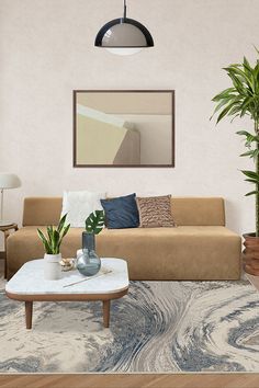 a living room with a couch, coffee table and potted plants on the floor