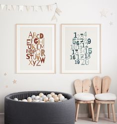 two framed art prints on the wall in a child's room with chairs and toys