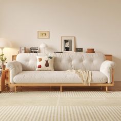 a white couch sitting on top of a wooden floor in a living room next to a lamp