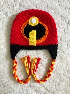 a crocheted hat with a yellow and red design on it sitting on top of a bed