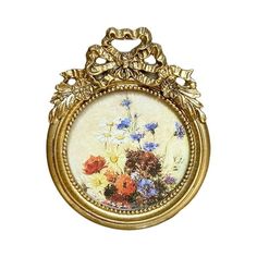 an ornate gold frame with flowers painted on the front and sides, hanging from a wall