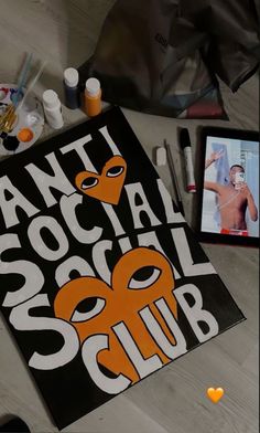 an orange and black sign with the words anti social social club on it next to other items