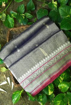 a gray and pink saree laying on top of green leaves