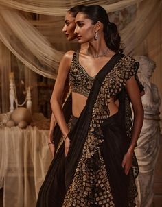 Radiate timeless elegance with this black sari adorned with luxurious ruffles and exquisite golden embroidery. The rich contrast between the deep black fabric and shimmering gold accents creates a stunning visual impact. Drape yourself in this masterpiece to showcase your impeccable style and celebrate the art of traditional craftsmanship with a modern twist. The blouse is crafted from net, while the sari itself is made from georgette. Drape Sari, Black Sari, Golden Embroidery, Black Drapes, Deep Black, Timeless Treasures, Photographic Lighting, The Deep, Black Fabric