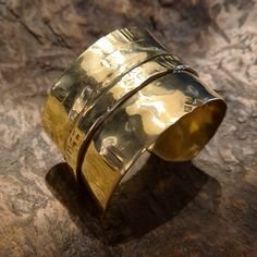 This unique and cool fold-formed brass wide cuff bracelet will always be the center of attention. Many of our designs are inspired by our fascination with the ancient cultures of the world, and this particular bracelet was inspired by the culture and lifestyle of the Vikings! This brutalist unisex cuff bracelet is made of brass. It is hammered, fold-formed, textured and polished entirely by hand in our studio. This handmade cuff bracelet is perfect for both women and courageous men... Its width is 4 cm. This cuff is adjustable, it can easily be squeezed for a tight fit or pried open for a looser fit. But even so, for its length, please select your size (considering the size of your wrist circumference) via the drop-down menu so that we can precisely prepare it for you.  Every piece in our Luxury Bronze Brass Bracelets, Luxury Bronze Cuff Bracelet As Gift, Gold Brass Wide Band Cuff Bracelet, Gold Brass Cuff Bracelet With Wide Band, Gold Wide Band Cuff Bracelet In Brass, Handmade Gold Cuff Bracelet With Wide Band, Handmade Wide Band Gold Cuff Bracelet, Gold Handmade Wide Band Cuff Bracelet, Gold Wide Band Handmade Cuff Bracelet