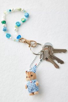 a keychain with a teddy bear wearing a party hat and holding two keys