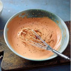 a bowl filled with batter and whisk on top of a wooden table