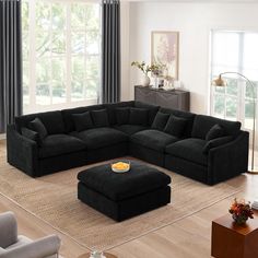 a living room with a large black sectional couch and footstool on the floor