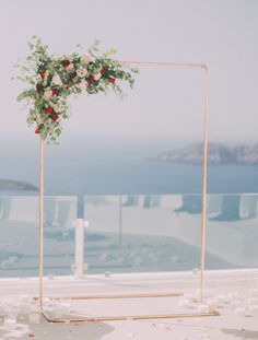 an outdoor ceremony setup with flowers and candles on the ground, overlooking the water in the background