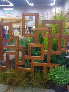 an assortment of wooden frames on display in a garden showroom with people looking at them