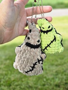 two crocheted sheep keychains are being held by someone's hand