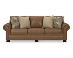 a brown leather couch with pillows on the armrests and two throw pillows in front of it