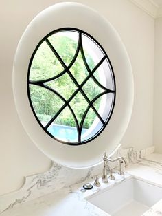 a round window in the corner of a bathroom with a sink and faucet